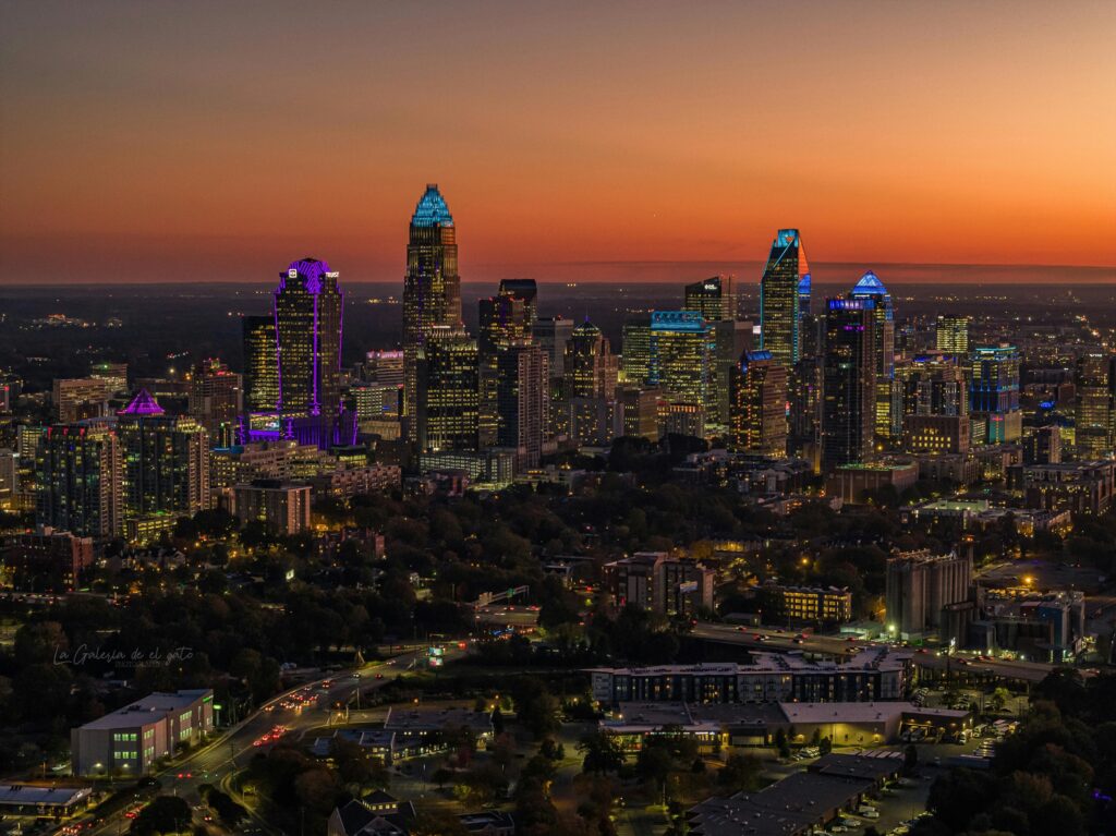 Aerial view of Charlotte cityscape with illuminated skyscrapers at twilight, showcasing urban beauty.