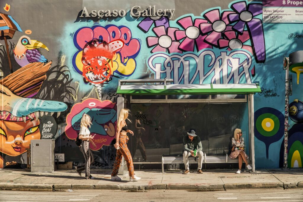 Colorful graffiti and bus stop scene outside Ascaso Gallery with people interacting.